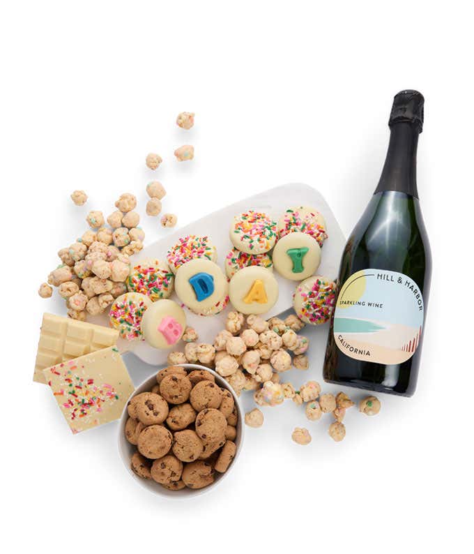 A gift with a bottle of sparkling wine, a dozen white chocolate covered Oreos with 4 spelling 